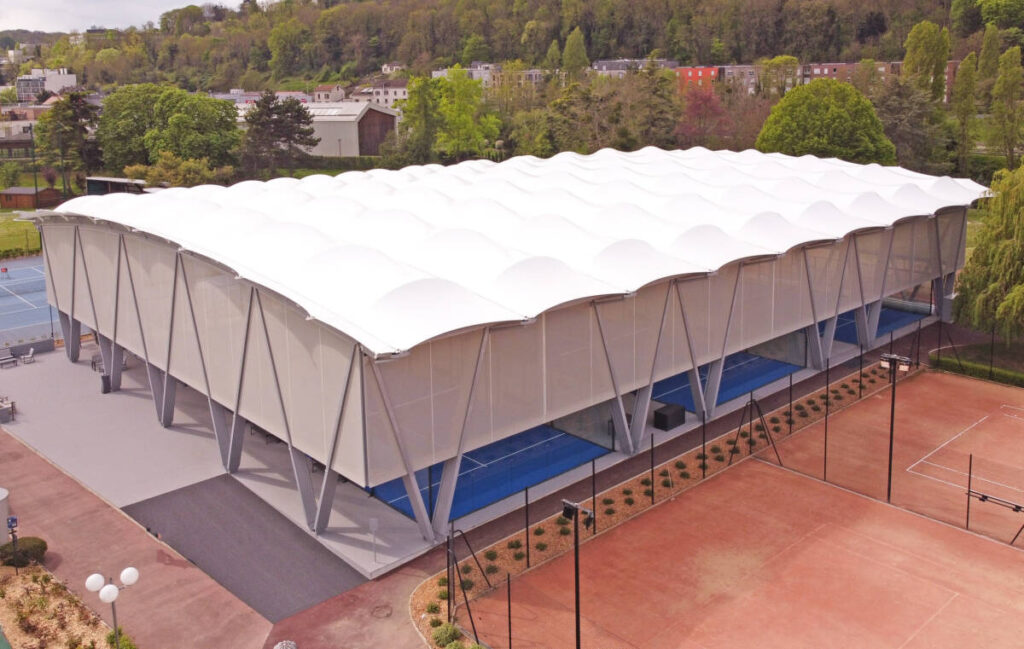 SMC2 covered five padel courts at Les Pyramides Club (Le Port-Marly) with a grey steel-and-timber structure and a durable, elegant textile membrane.