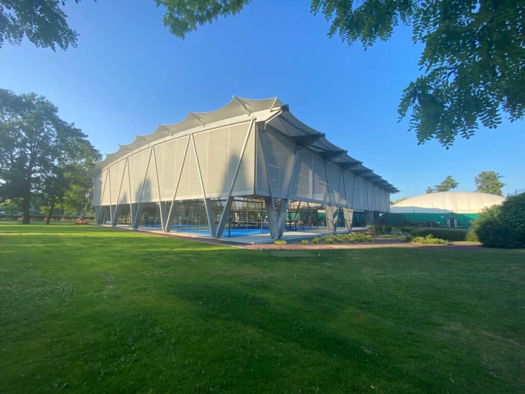 SMC2 covered five padel courts at Les Pyramides Club (Le Port-Marly) with a grey steel-and-timber structure and a durable, elegant textile membrane.