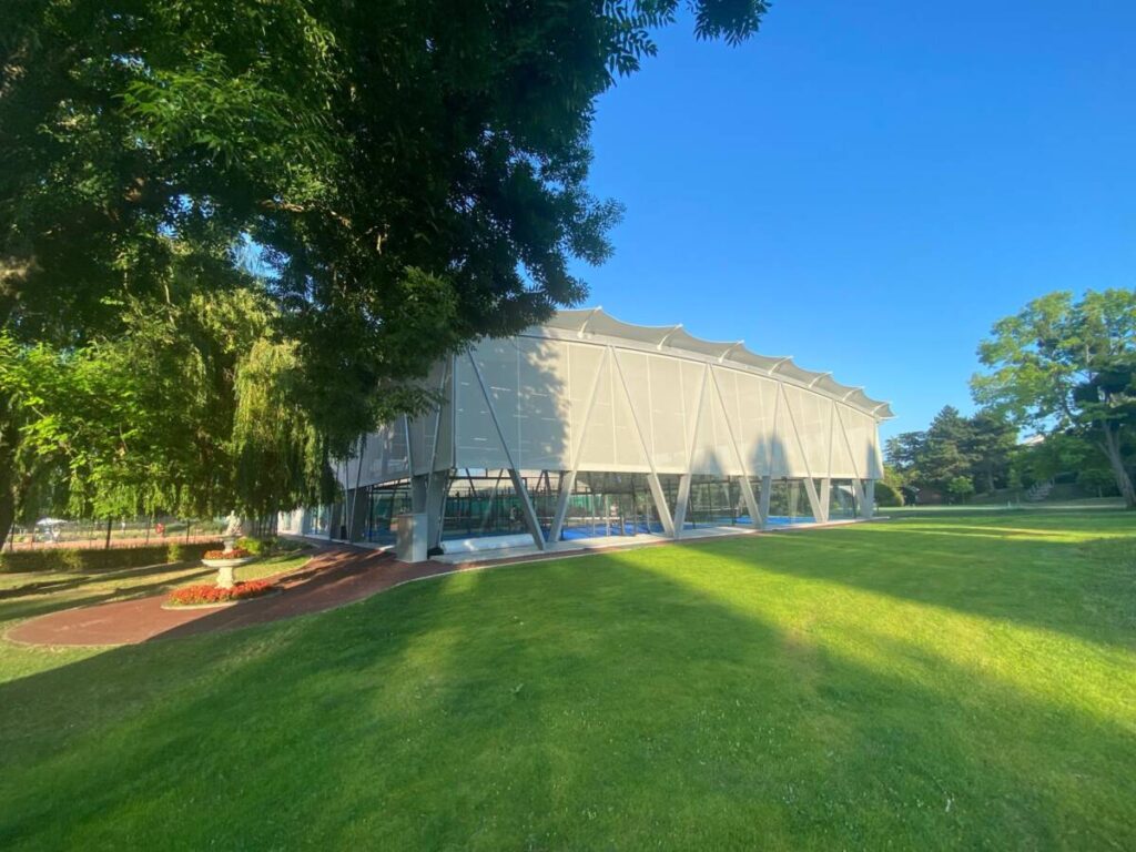 SMC2 covered five padel courts at Les Pyramides Club (Le Port-Marly) with a grey steel-and-timber structure and a durable, elegant textile membrane.